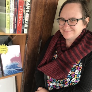A smiling woman standing outside a bookshop